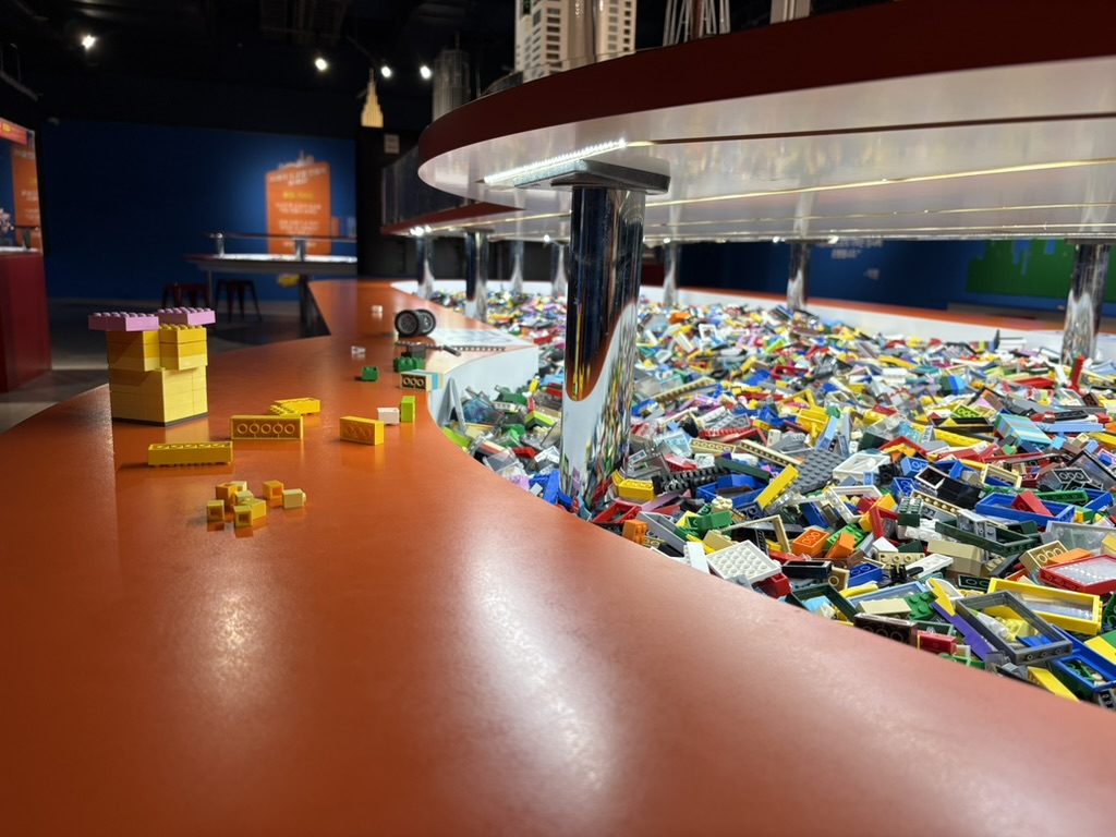 Huge round free-build table overflowing with loose LEGO bricks at Brickman