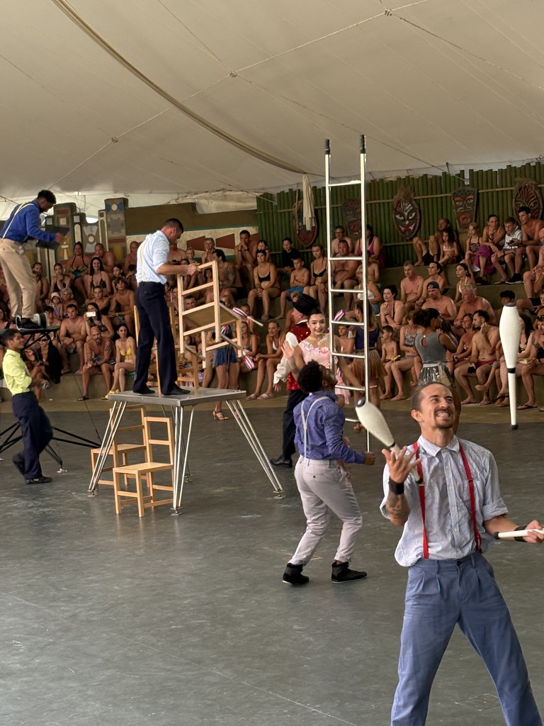 Jugglers with clubs performing in front of the seated audience at Caribe Bay's theatre