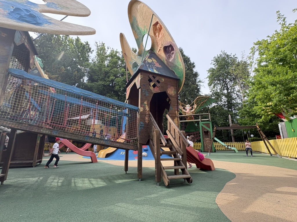Gardaland kids' playground — large wooden treehouse structure with net bridges, slides, and flying saucer decorations