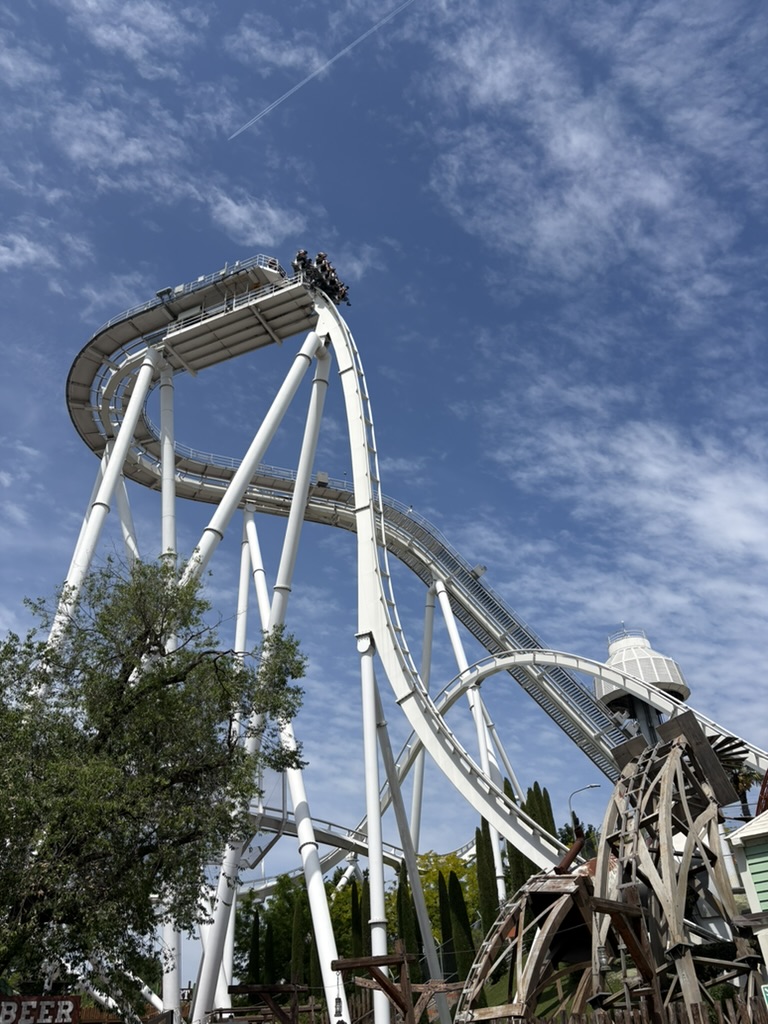 Tall white roller coaster at Gardaland reaching high into the sky with steep drop