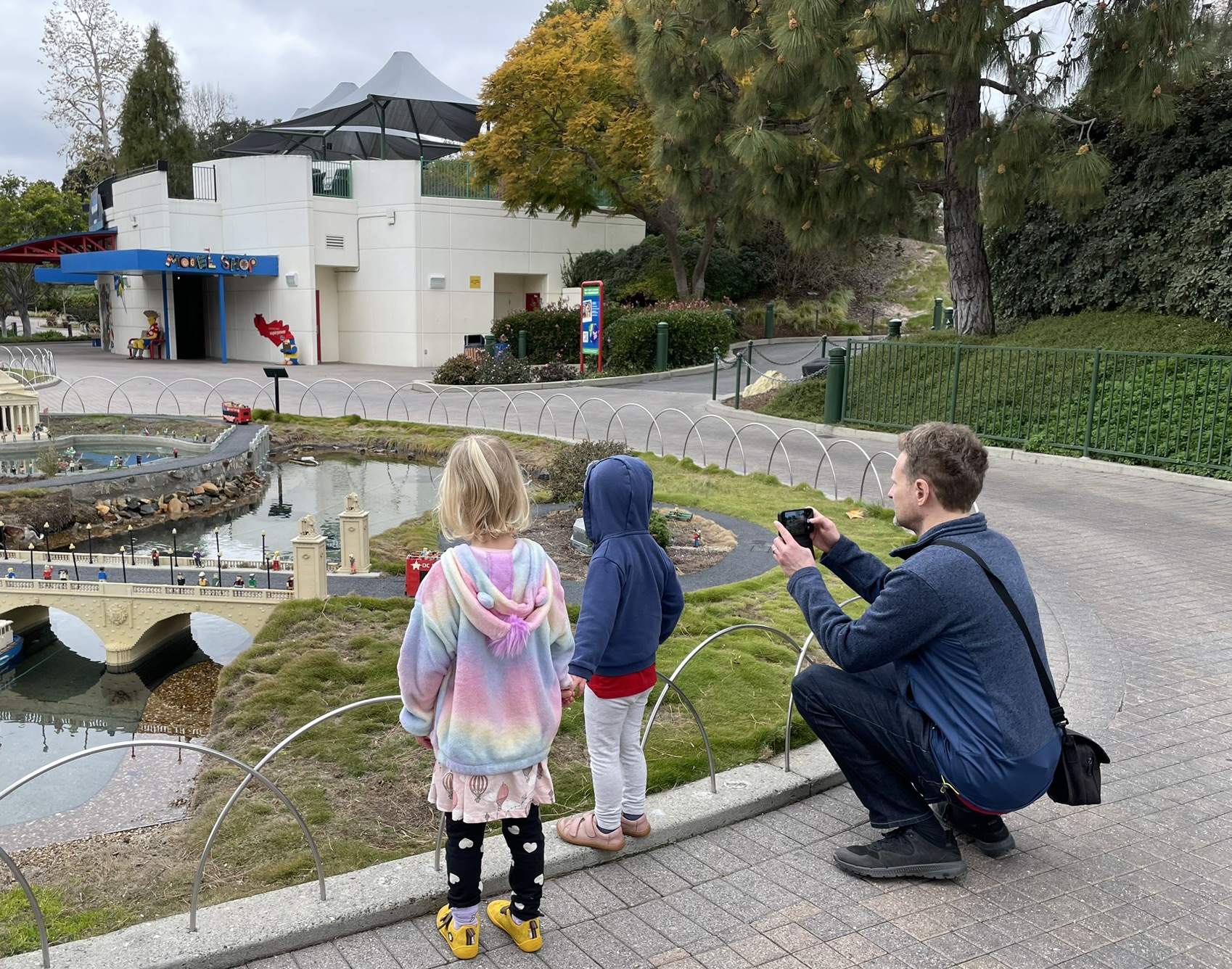 Two kids and their dad looking at the LEGO Miniland USA display at Legoland California, featuring a miniature European city with bridges and boats