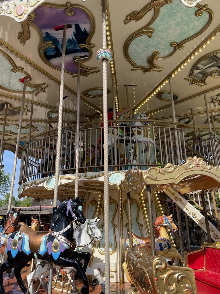 Ornate two-storey carousel at Energylandia with painted horses, gold detailing, and rows of lights