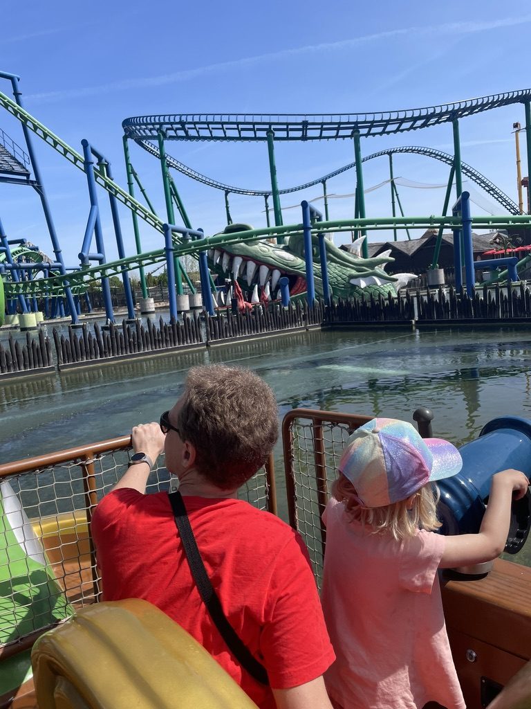 A green dragon-themed rollercoaster winding over water at Energylandia, seen from a boat ride