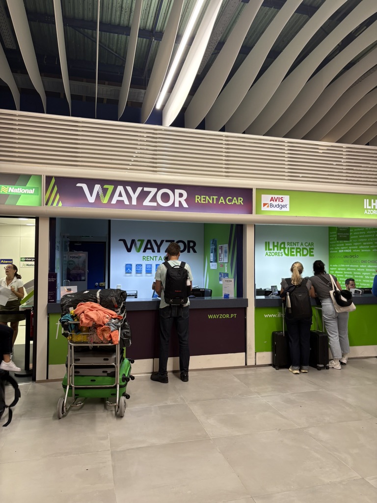 Wayzor rental car desk at Ponta Delgada Airport with a short line of travelers