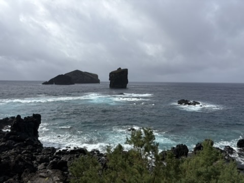 Two rocky sea stacks off the coast near Mosteiros, Azores, under a cloudy sky