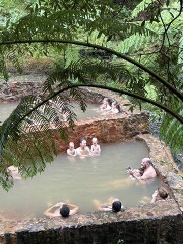 Family with young kids swimming in the warm volcanic pools at Caldeira Velha, Azores