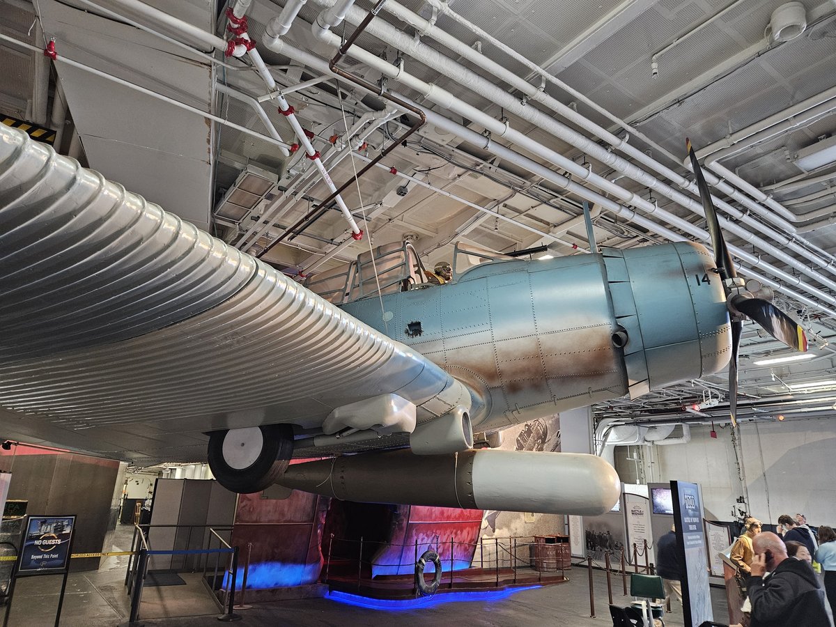 A WWII-era aircraft suspended from the ceiling of the USS Midway hangar bay