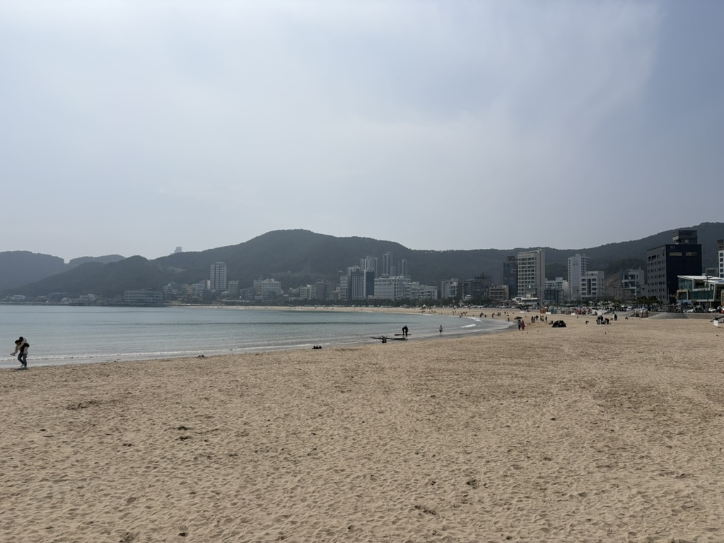 Songjeong Beach with wide sandy shore and mountains behind, Busan