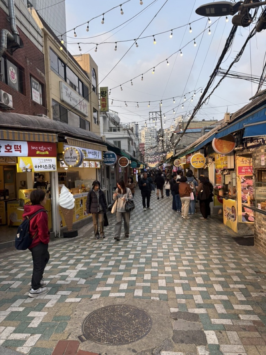 A Korean street food alley lined with stalls and hanging lights