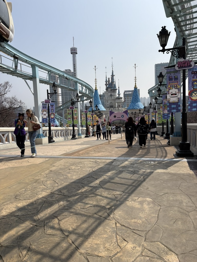 Magic Island outdoor walkway at Lotte World with castle spires and roller coaster track