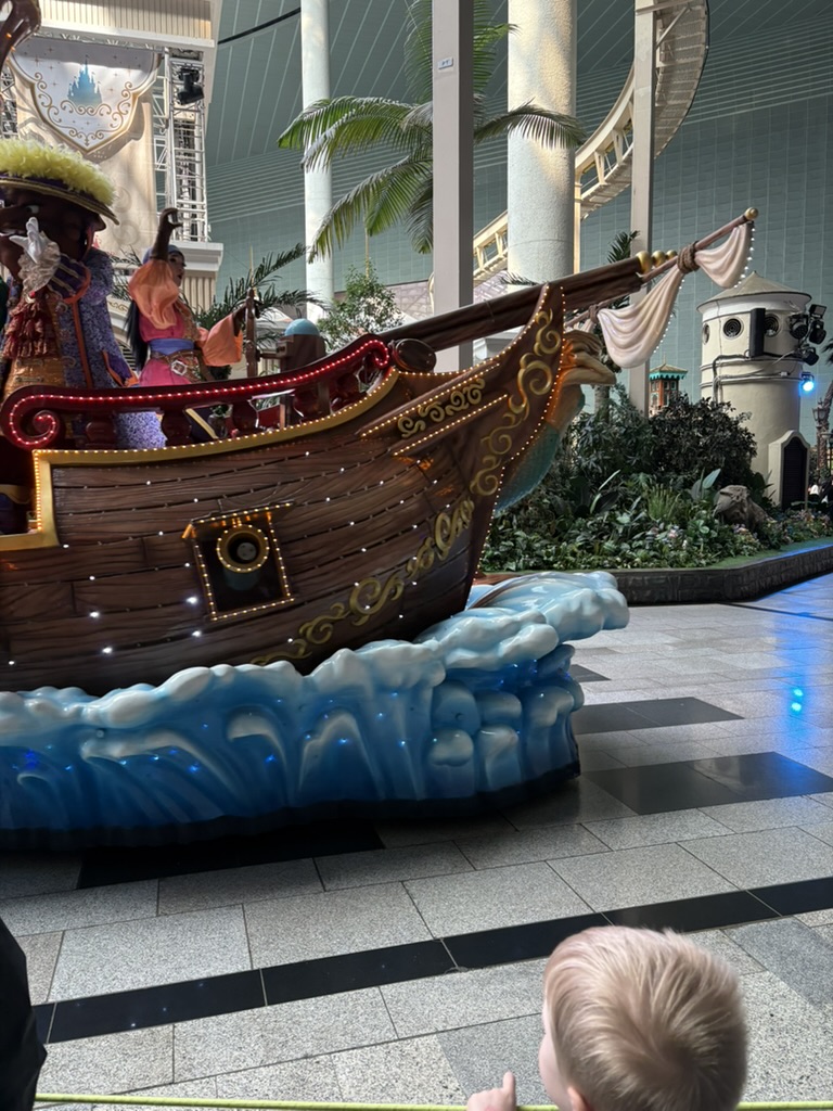 Lotte World indoor parade — lit-up pirate ship float with child watching in foreground